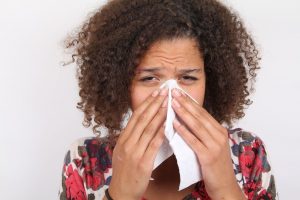 Woman with allergies blowing her nose
